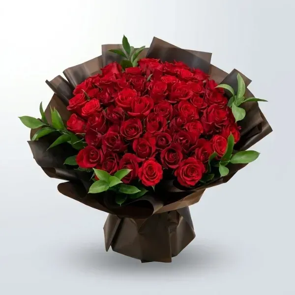 Luxury red rose bouquet wrapped in translucent dark brown and black paper with fresh green foliage