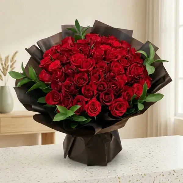 Luxury red rose bouquet wrapped in translucent dark brown and black paper with fresh green foliage
